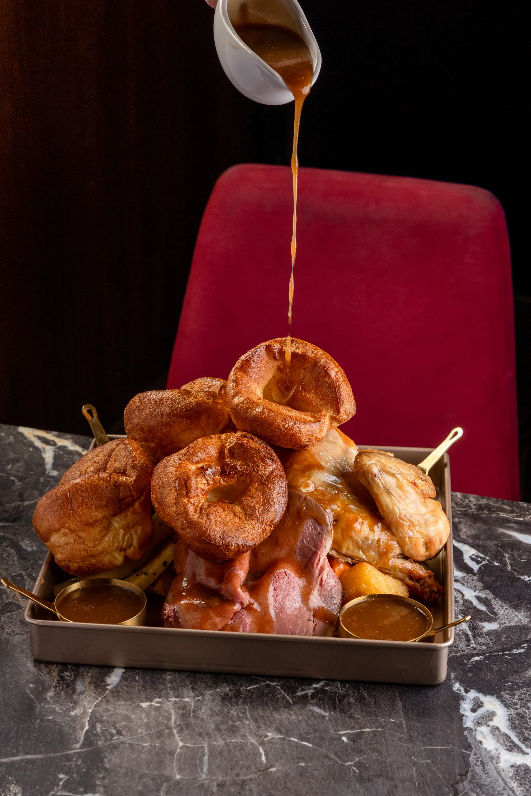 Gravy being poured over a Sunday roast sharing platter